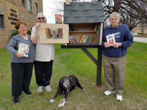 Ginger Cook, Linda Maylone, and Paul Cook show off the inside of their Little Free Library.