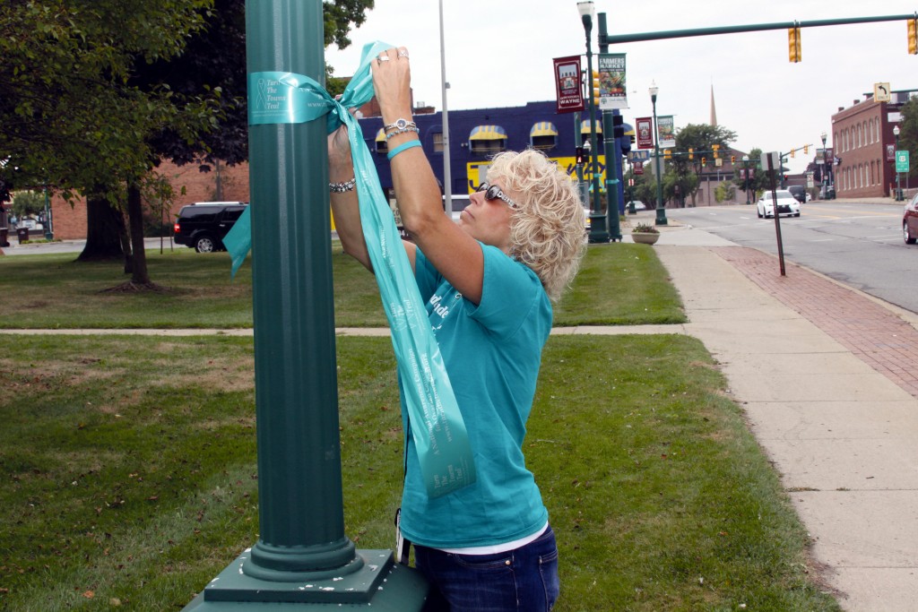 Cathy Buchanan ties ribbons on downtown poles for National Ovarian Cancer Awareness Month. 