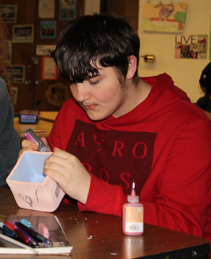 A Tinkham student paints a bowl for the Empty Bowls Project.
